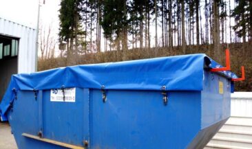 Blauer Abfallcontainer mit einer blauen Plane, die den Inhalt abdeckt und mit Clips gesichert ist.