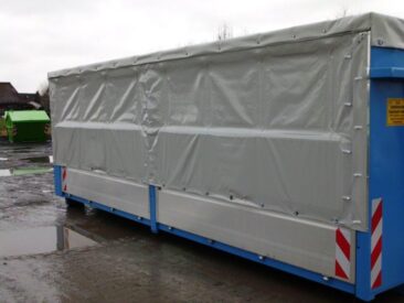Blauer Container mit einer grauen Planenabdeckung, die teilweise heruntergelassen ist.