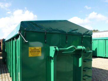 Grüner Abfallcontainer mit einer grünen Plane und einem gelben Schild zur Kennzeichnung.
