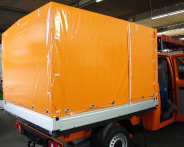 Orange Plane, die ein Transportfahrzeug abdeckt, mit stabilen Befestigungen und einer glatten Oberfläche.