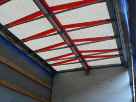 Innenansicht eines Lkw mit einem weißen Planenverdeck und roten Streifen auf der Decke.