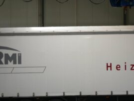 Weißer Lkw-Anhänger mit dem Schriftzug 'Heizsysteme' auf der Seite.