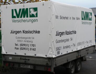 Ein Anhänger mit einer weißen Plane, die Werbung für LVM Versicherungen zeigt.