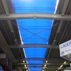 Blaue Abdeckung über einem Lagerbereich mit sichtbarem Dach und Beleuchtung.