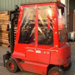 Roter Gabelstapler mit geschlossener Kabine und transparenten Seitenwänden.